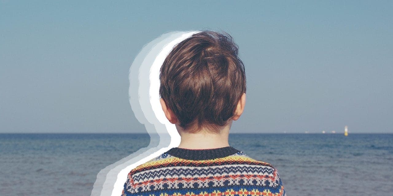 a child's back fronting a beach